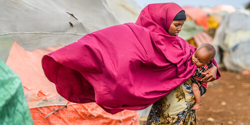 Eine Frau hält in einem Geflüchtetencamp in Somalia ein Kind auf dem Arm Eine Frau hält in einem Geflüchtetencamp in Somalia ein Kind auf dem Arm